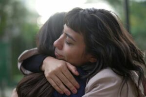 two women hug each other while outside and enjoying outdoor activities in their women's rehab program