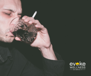 Haggard looking man drinking alcohol from a glass while clutching a cigarette about to learn what does browning out mean